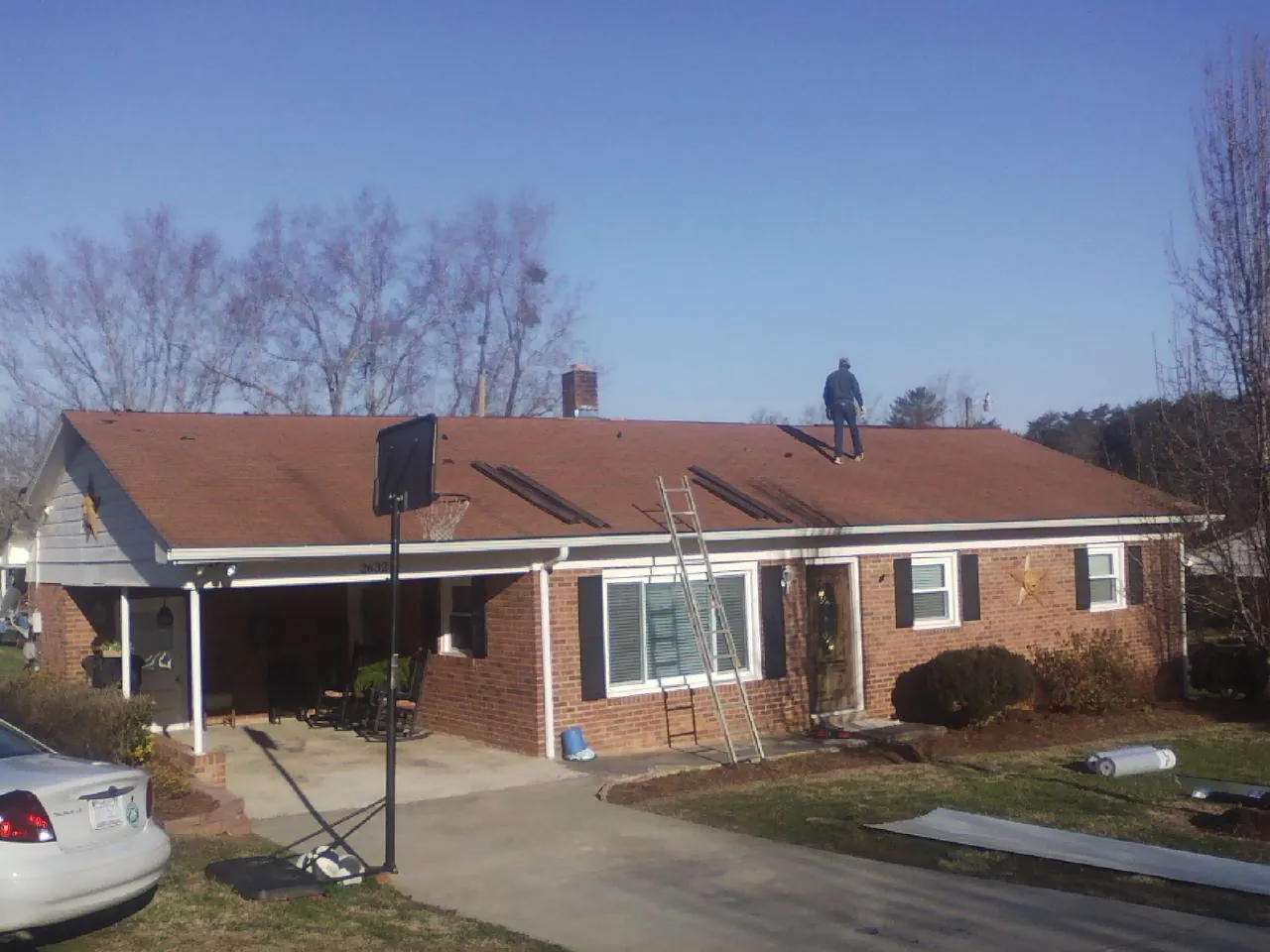 Roofer stripping a shingle roof on a brick ranch before metal panels in Chester